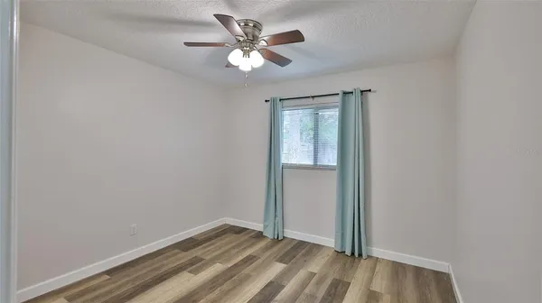 an empty room with a chandelier fan and a window