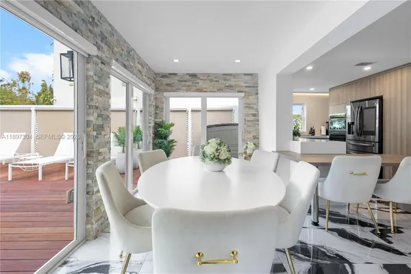 a large white dining room with stainless steel appliances a table and chairs