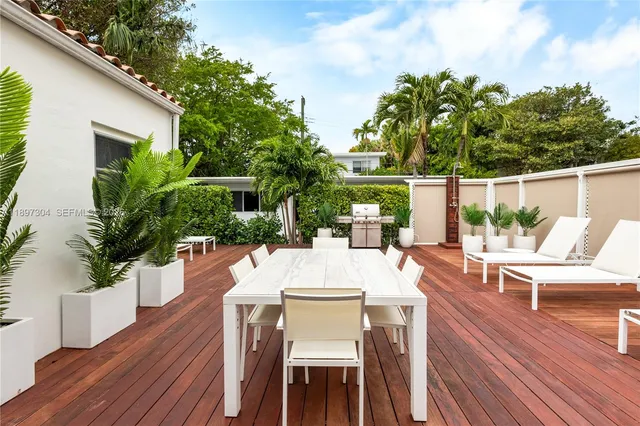 a view of a patio with table and chairs and potted plants with wooden floor and fence