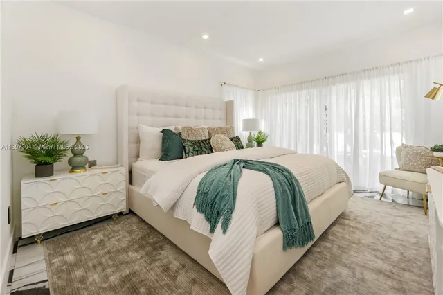 a bed sitting in a spacious bedroom next to a window and dresser