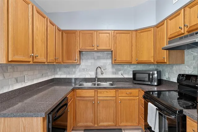 a kitchen with granite countertop a refrigerator and a stove top oven