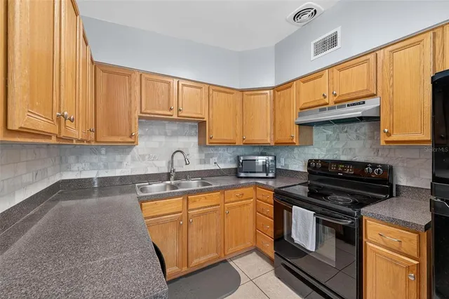 a kitchen with a refrigerator a stove top oven a sink and a window