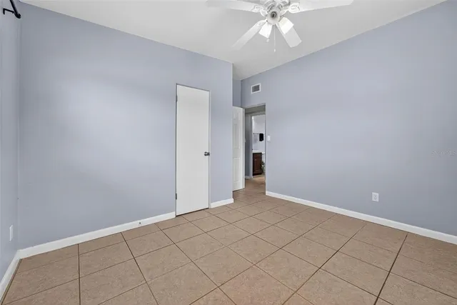 a view of an empty room with window and chandelier fan
