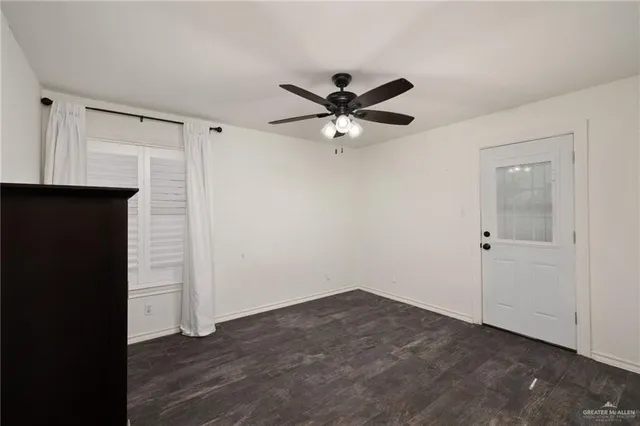 a view of an empty room with a window and wooden floor