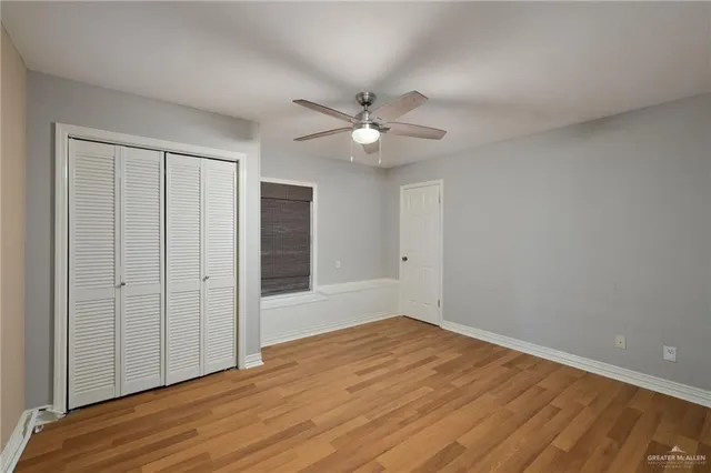 a view of empty room with wooden floor and ceiling fan