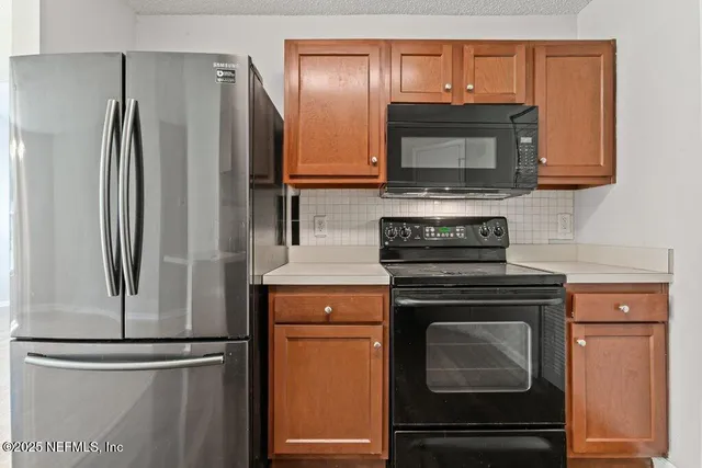 a kitchen with granite countertop a refrigerator stove and microwave