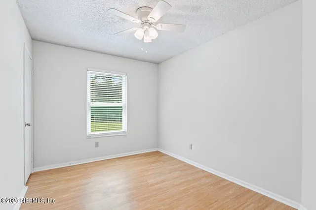 an empty room with a window and a fan