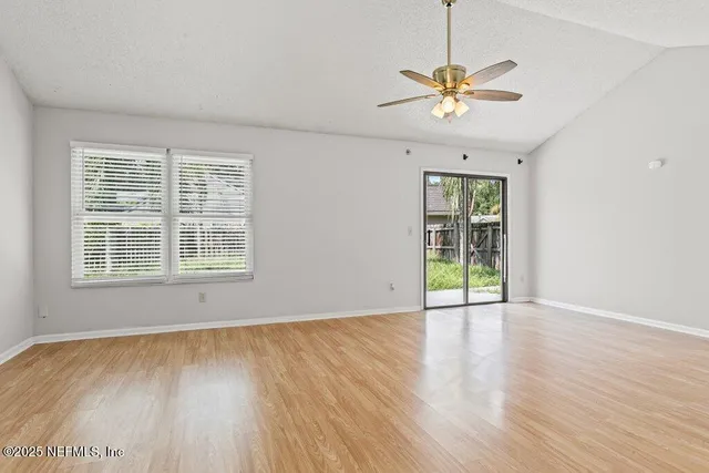 a view of an empty room with a window and wooden floor