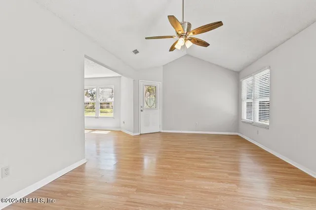 an empty room with wooden floor closet and windows