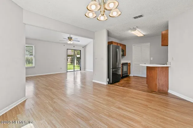 an empty room with wooden floor closet and windows