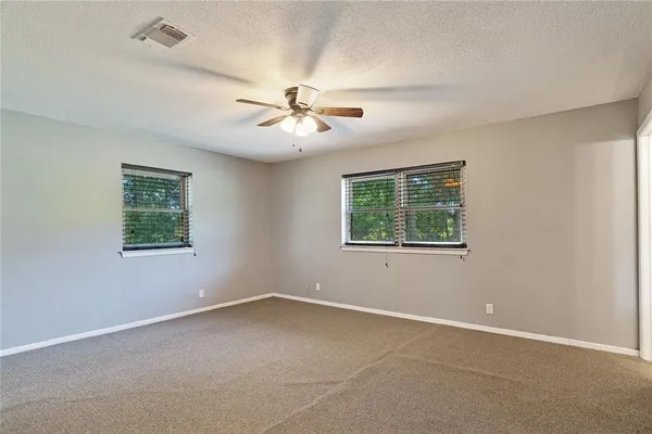 an empty room with a window and a ceiling fan