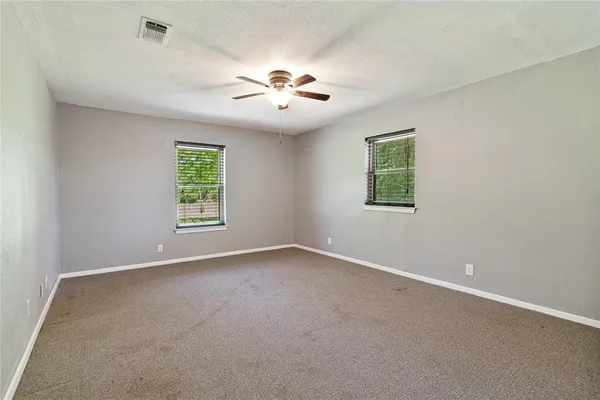 an empty room with windows and chandelier fan