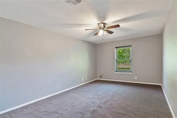 an empty room with a window and a ceiling fan
