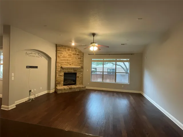 an empty room with wooden floor fireplace and windows