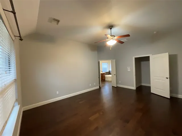 an empty room with wooden floor ceiling fan and window