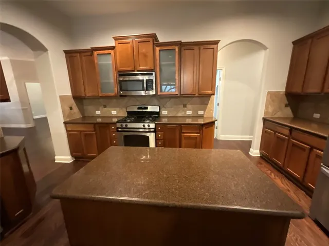 a kitchen with stainless steel appliances a stove a sink a microwave a refrigerator a sink a stove and island