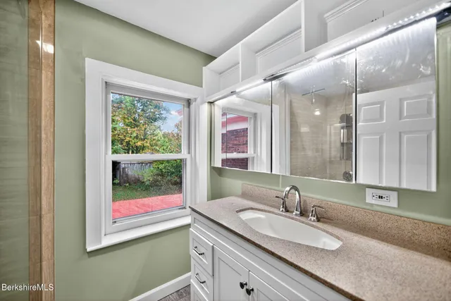 a bathroom with a granite countertop sink mirror and window