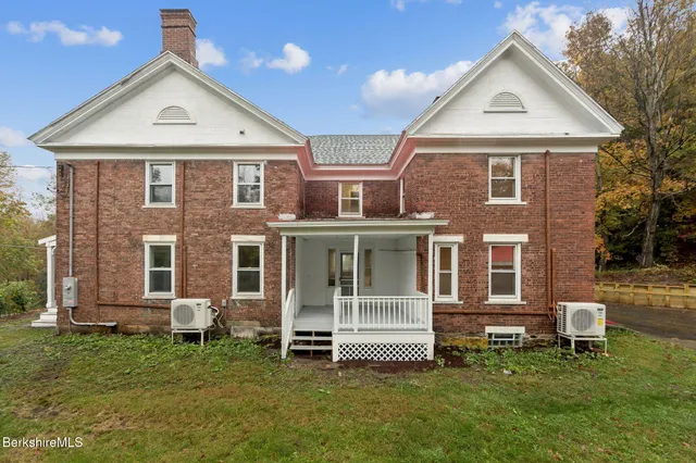 a view of a brick house with a yard and large trees