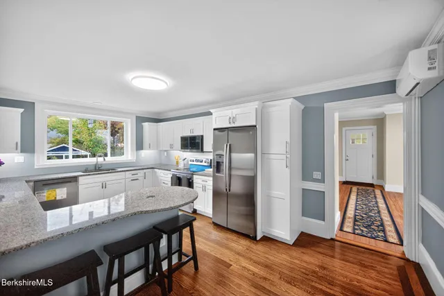 a kitchen with stainless steel appliances wooden floor and large window