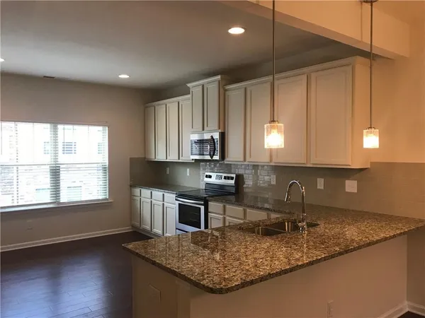 a kitchen with kitchen island granite countertop a sink cabinets and wooden floor