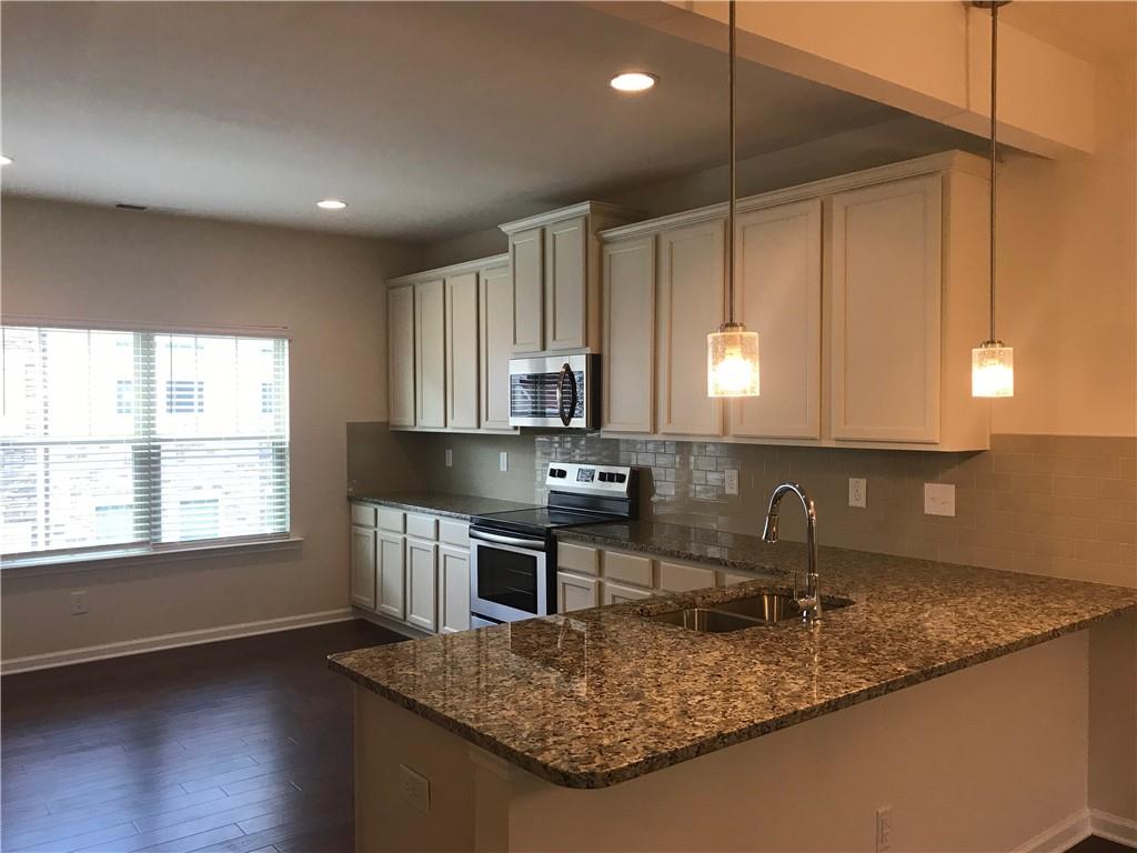 3844 Equity Lane Powder Springs, GA 30127 - Photo 12 of 38 a kitchen with kitchen island granite countertop a sink cabinets and wooden floor