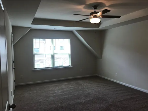 en empty room with windows and ceiling fan