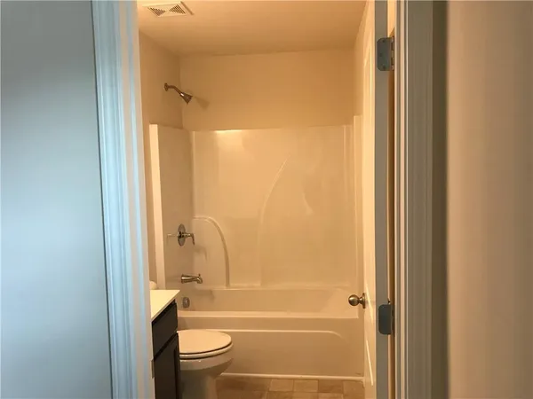 a bathroom with a tub shower sink vanity and a toilet