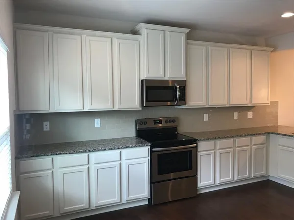 a kitchen with white cabinets and black appliances