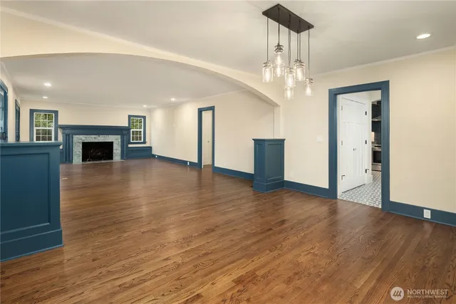 a view of an empty room with wooden floor fireplace and a window