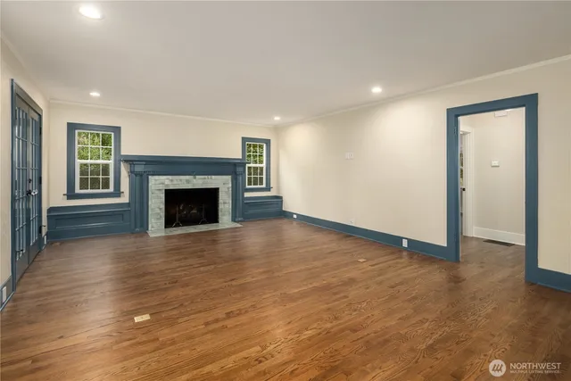 an empty room with wooden floor fireplace and windows