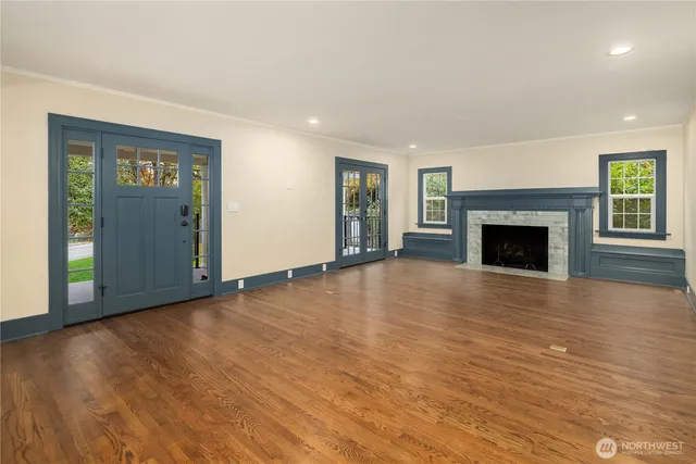 an empty room with wooden floor fireplace and windows