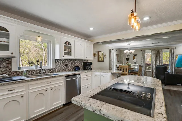 a large kitchen with a stove a sink dishwasher a dining table and chairs with wooden floor