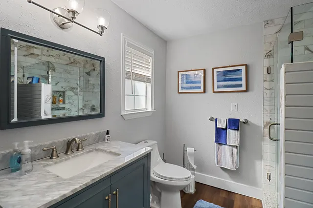 a bathroom with a granite countertop sink mirror vanity and toilet