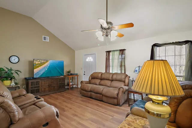 a living room with stainless steel appliances granite countertop furniture wooden floor and a kitchen view