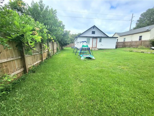 a white house that has a small yard and a large tree
