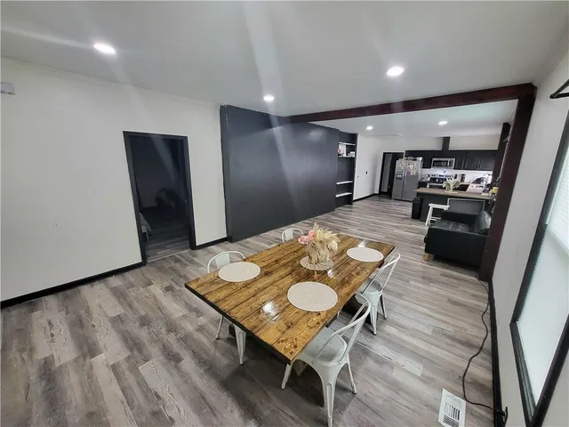 a kitchen with stainless steel appliances kitchen island granite countertop furniture wooden floor and a refrigerator