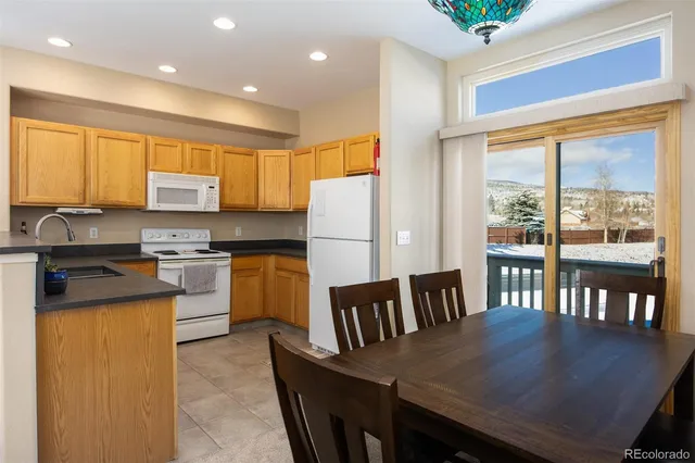 a kitchen with granite countertop a stove a refrigerator a sink a dining table and chairs with wooden floor