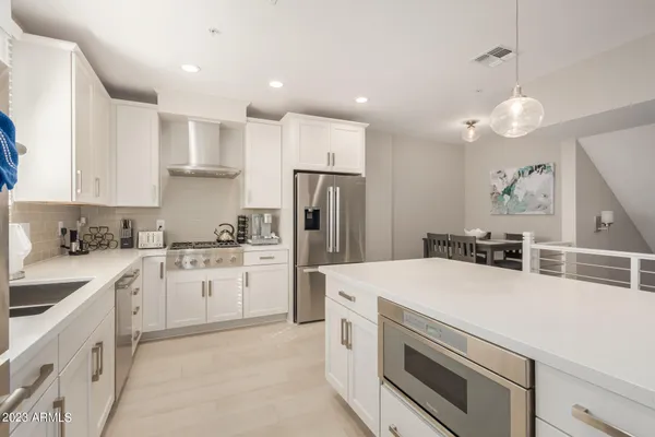 a kitchen with stainless steel appliances granite countertop a refrigerator a sink and white cabinets