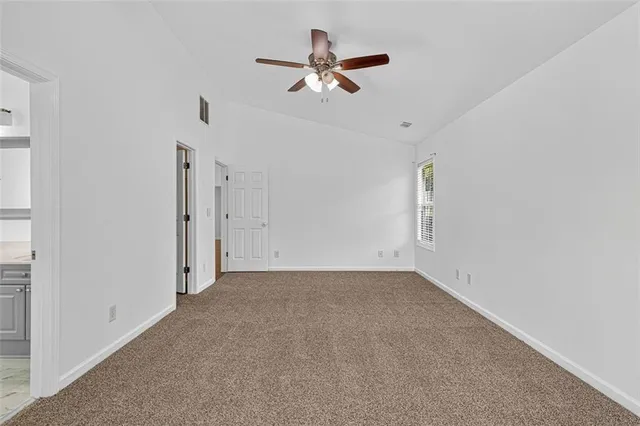 an empty room with closet and a ceiling fan