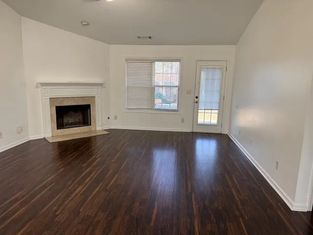 an empty room with wooden floor fireplace and windows