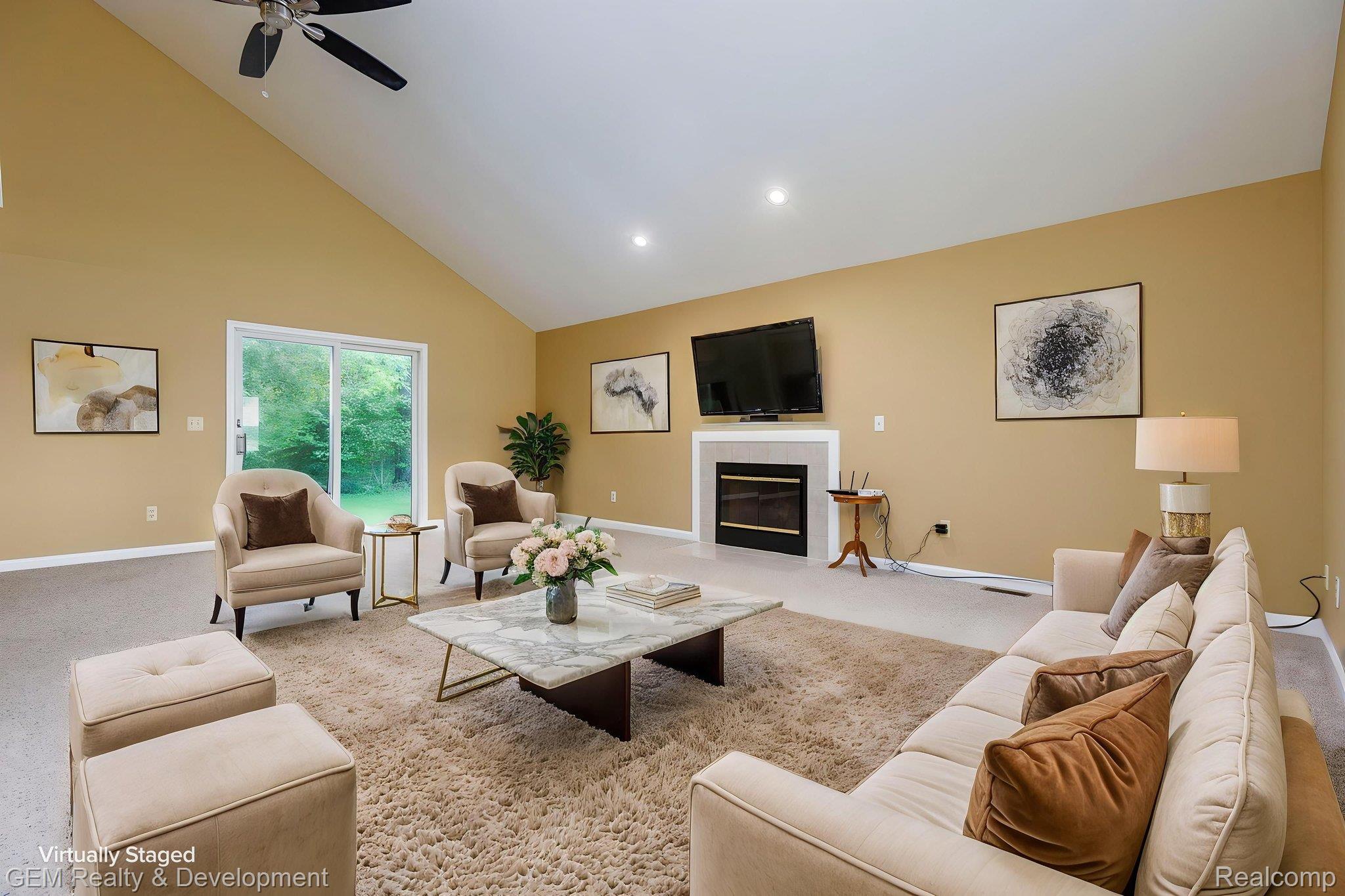 1111 Sarah Pinckney, MI 48169 - Photo 5 of 39 Spacious living area featuring a vaulted ceiling with a ceiling fan, a fireplace with a white mantel, and light-colored carpeting