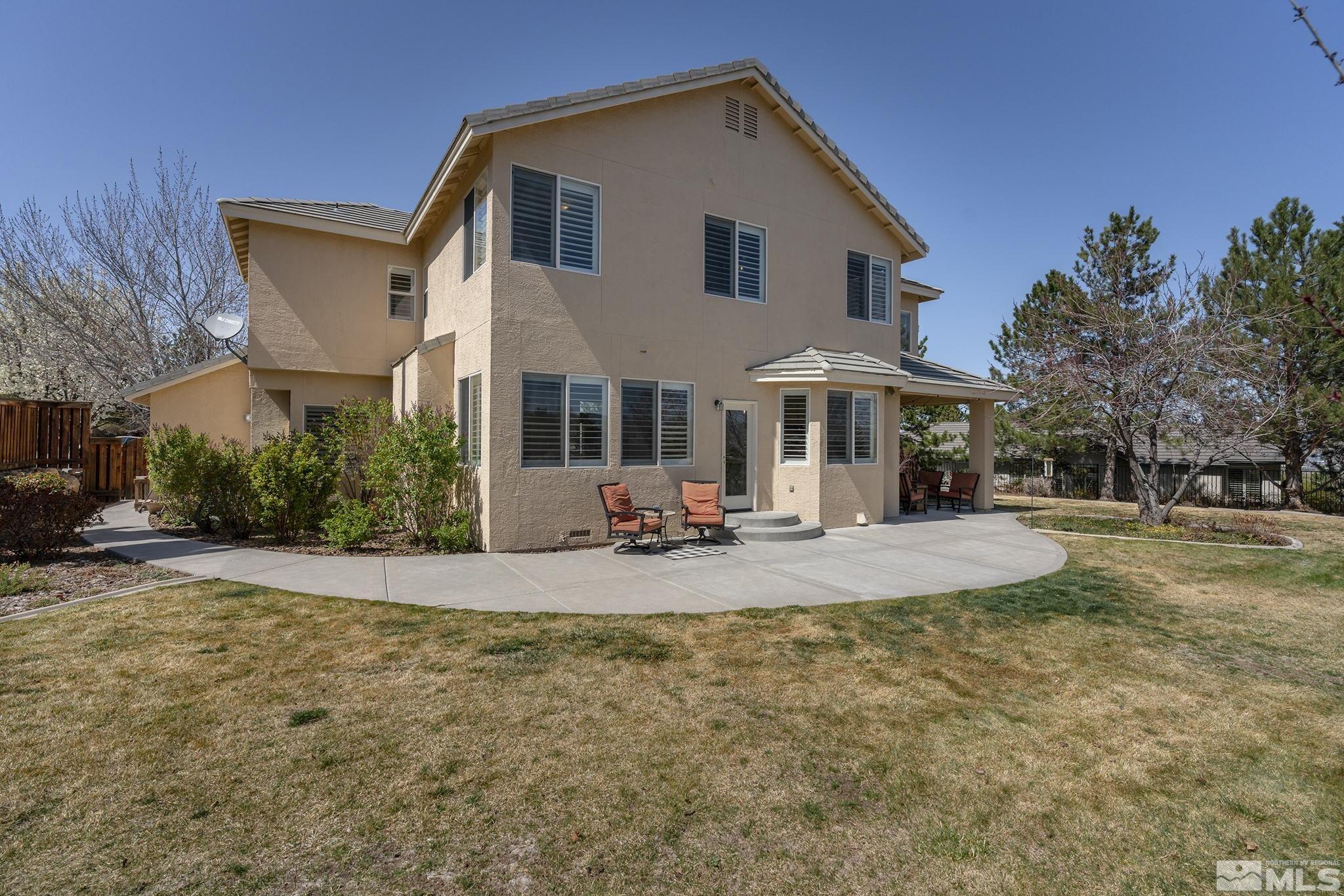 5016 East Albuquerque Road Reno, NV 89511 - Photo 32 of 38 a view of a white house with large windows and a table and chairs under an umbrella
