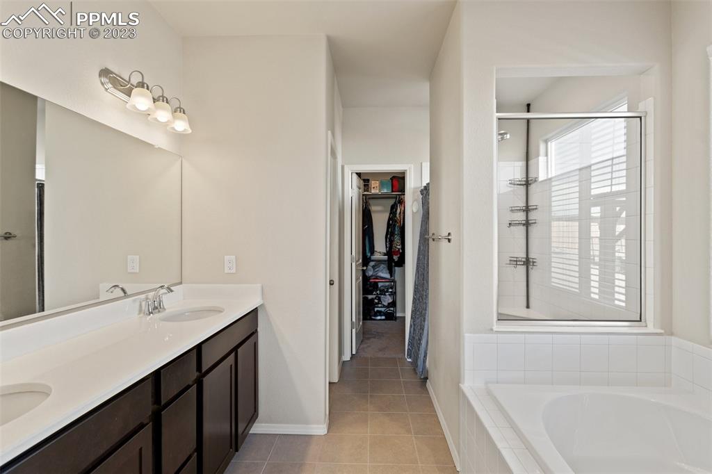 10095 Keating Drive Peyton, CO 80831 - Photo 11 of 31 a bathroom with a double vanity sink a mirror and a bathtub