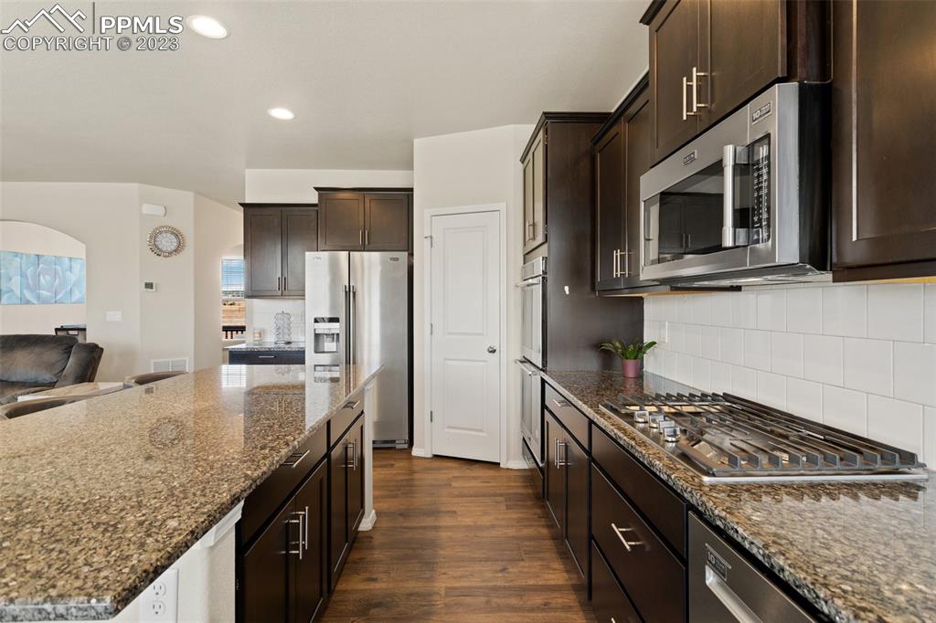 10095 Keating Drive Peyton, CO 80831 - Photo 7 of 31 a kitchen with stainless steel appliances granite countertop a stove refrigerator and microwave