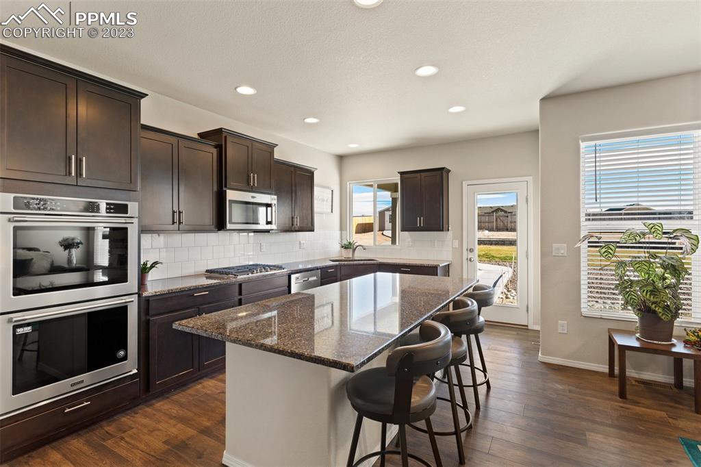 10095 Keating Drive Peyton, CO 80831 - Photo 8 of 31 a kitchen with granite countertop stainless steel appliances a stove a sink a refrigerator cabinets and dining table