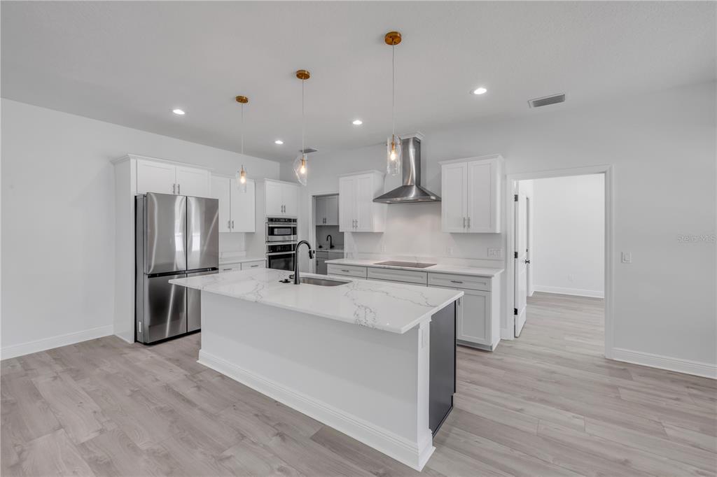 2324 Orange Tree Drive Edgewater, FL 32141 - Photo 16 of 59 a open kitchen with kitchen island a stove a sink dishwasher a refrigerator and white cabinets with wooden floor