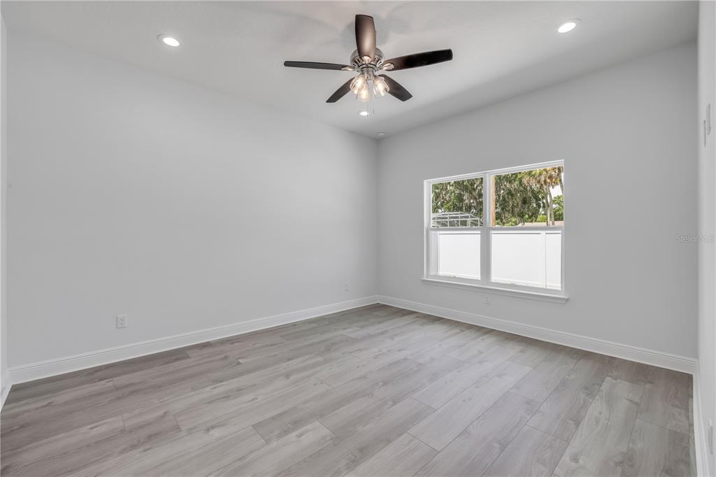 2324 Orange Tree Drive Edgewater, FL 32141 - Photo 28 of 59 an empty room with wooden floor chandelier fan and windows