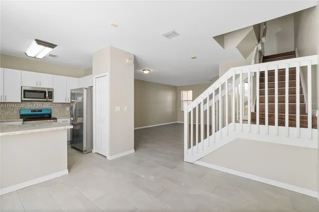 a view of a kitchen with a refrigerator a stove top oven cabinets