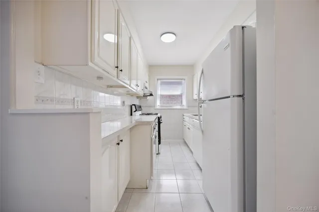 a kitchen with white cabinets and refrigerator