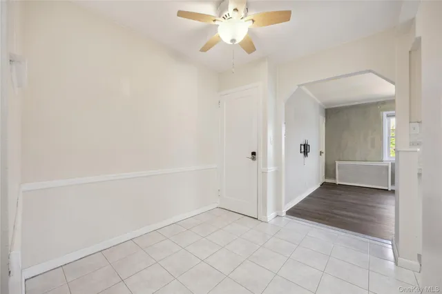 wooden floor in an empty room with a chandelier fan